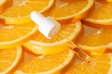Vitamin C serum in a pipette with white cap on a background of orange citrus fruits. Citrus essential oil, aromatherapy cosmetics. Organic SPA cosmetics with herbal ingredients