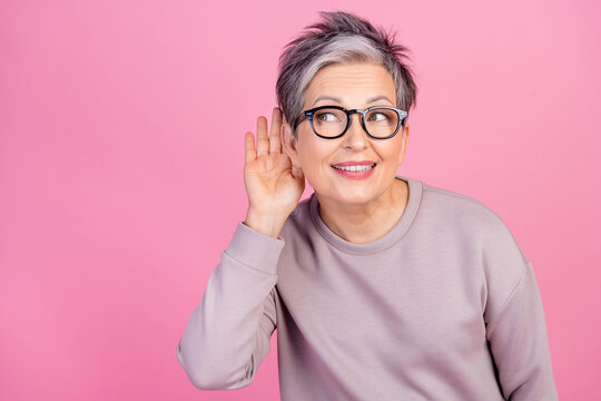 Close up photo of senior lady ombre haircut wearing sweatshirt touch ear doing eavesdropping look novelty isolated on pink color background