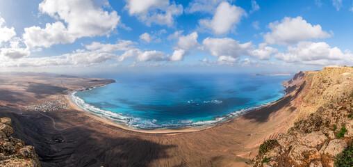 Sweeping views of Playa Famara, Lanzarote, with its golden sands embraced by azure waters and...