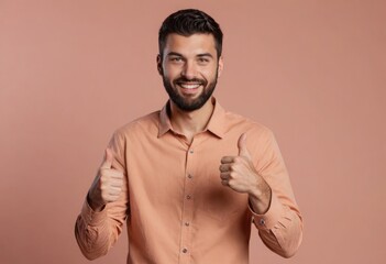 Fototapeta premium A joyful man with a beard gives a double thumbs up in front of a peach background.