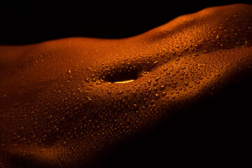 drops of sweat and water on an athletic body in low key