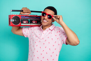 Portrait of positive person toothy smile arm touch sunglass carry boombox isolated on turquoise color background