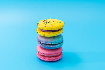 Brightly colored stacked macarons on blue background. Tasty colorful macaroon assorted. Three sweet macaroons cakes of different colors. Delicious dessert. Culinary, cooking concept.