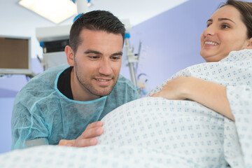 husband looking lovingly at wifes bump during childbirth