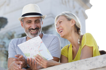 senior couple on holiday laughing togather while looking at map