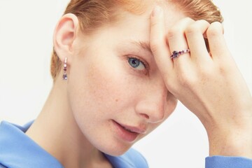 Close up portrait of a beautiful elegant woman with freckles with stylish jewelry on a white...