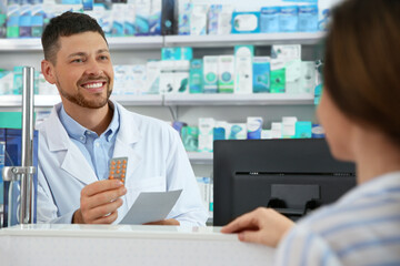 Professional pharmacist working with customer in drugstore
