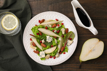 Delicious pear salad with sauce on wooden table, flat lay