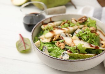 Delicious pear salad with sauce in bowl on white wooden table, closeup