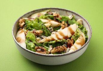 Delicious pear salad with sauce in bowl on green background, closeup