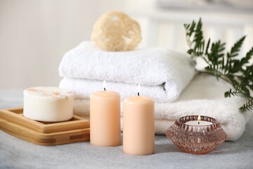 Spa composition. Burning candles, soap, towels and loofah on soft grey surface