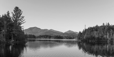 Kayaking in Boreas Ponds in the Adirondacks on a glassy lake with Mount Marcy and the high peaks in the background as the sun is setting.