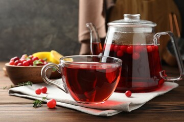 Tasty hot cranberry tea and fresh berries on wooden table