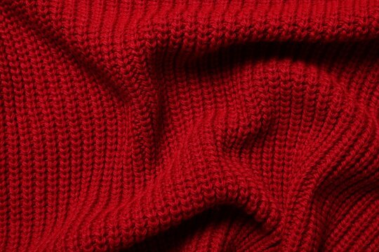 Texture of soft red knitted fabric as background, top view