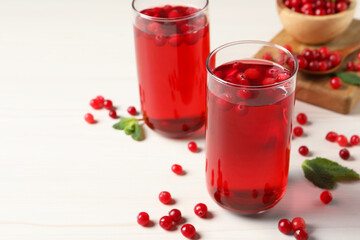 Tasty cranberry juice in glasses and fresh berries on white wooden table, closeup. Space for text