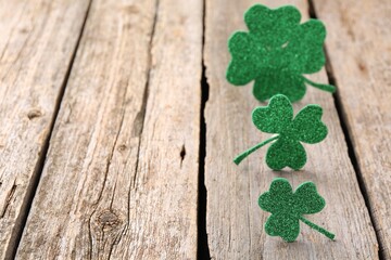 St. Patrick's day. Shiny decorative clover leaves on wooden table, selective focus. Space for text