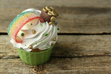 St. Patrick's day party. Tasty cupcake with sour rainbow belt and pot of gold toppers on wooden...