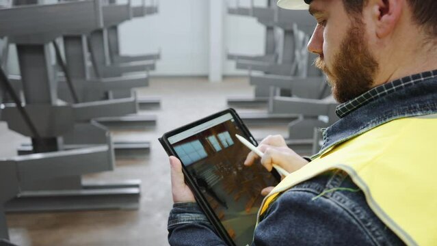 The quality manager engineer checks the constructed metalwork object for compliance with the 3D model in the tablet.