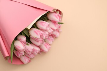 Beautiful bouquet of fresh pink tulips on beige background. Space for text