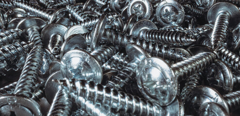 A bunch of metal screws on a black background. Metal screws background, made of stainless steel