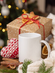 Obraz na płótnie Canvas White coffee mug near Christmas present, cosy heart and sweater, winter atmospheric mockup