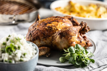 A whole roasted chicken on the table together with jasmine rice and baked potatoes - 742798446
