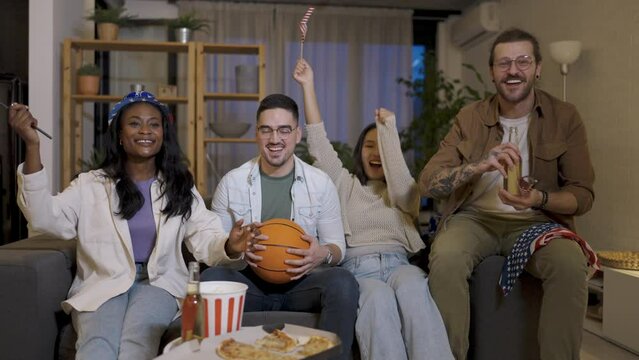 Multiracial group of friends watching basketball game, drinking beer and cheering.
