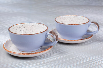 Ceramic clay cups and saucers on a gray background.