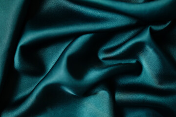 Emerald green silk or satin, draped fabric, elegant background.