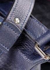 Part of a blue leather bag on a black background. Leather goods.