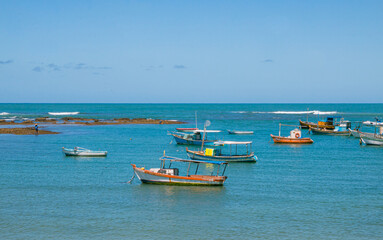 Fototapeta na wymiar beach with boats in the sea with cloudless blue sky and space for text