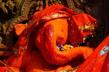 sculpture of red ganesha wearing red chunri