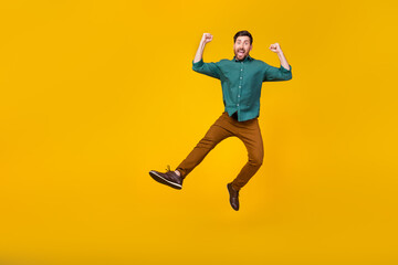 Fototapeta na wymiar Full size photo of satisfied guy dressed dotted shirt brown pants fly win bet fists up screaming isolated on yellow color background