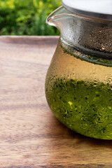 汗をかいたガラスのポットに入った冷たい水出し緑茶
