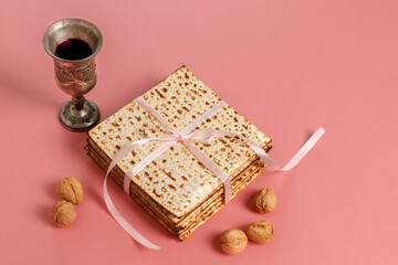 Matzah, walnuts and glass of wine on pink background. Jewish holiday Pesach