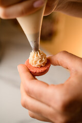 Confectioner's hands apply cream to the macaroon blank