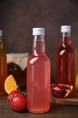 Delicious kombucha in glass bottles and fresh fruits on wooden table