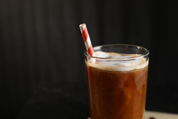 Refreshing iced coffee with milk in glass against dark gray background, closeup. Space for text
