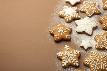 Fototapeta na wymiar Tasty Christmas cookies with icing and powdered sugar on brown background. Space for text