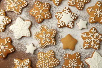 Tasty Christmas cookies with icing and powdered sugar on brown background, flat lay