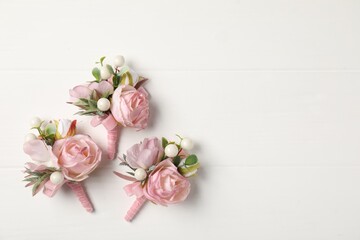 Beautiful boutonnieres on white background, flat lay. Space for text