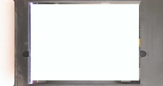 Operation of a flatbed scanner with sheet of paper in open mode. Movement of the head, lamp. Close-up. Top view.