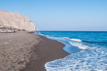 volcanic black sand beach on santorini island in greece and aegean sea