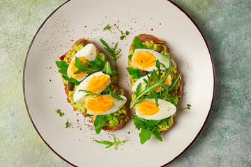 sandwich with mashed avocado, boiled egg, and arugula, on bread , homemade, breakfast,