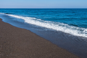 volcanic black sand beach on santorini island in greece and aegean sea