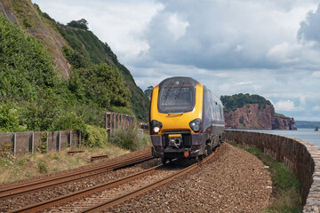 A passenger service travelling along the spectacular coastal railway route adjacent to the walkway between Dawlish and Teignmouth in Devon UK