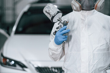 Focused close up view. Man is holding spray gun for painting a car