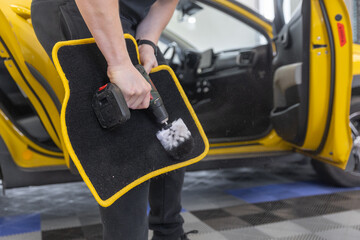 Process of cleaning a car mat by an automatic brush cleaner, car detailing concept