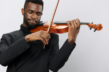 A talented African American man in a classic black suit playing the violin gracefully on a clean...
