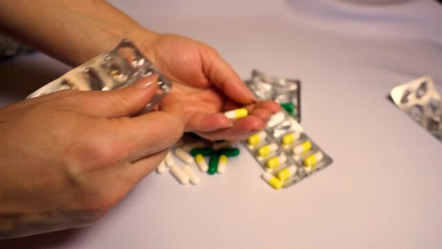 A woman pours pills from a medicine bottle into her hand while taking medicine, Danger of overdose, drug addiction. Concept of medicine, public health and the pharmaceutical industry. 